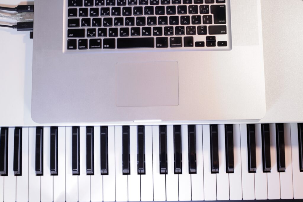 デスクでMIDIキーボードを使ってDAWで楽曲を打ち込んでいる様子